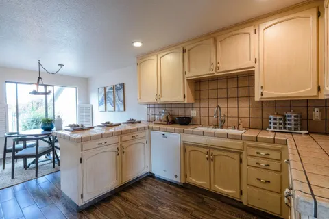 a kitchen with a stove a sink and white cabinets with wooden floor