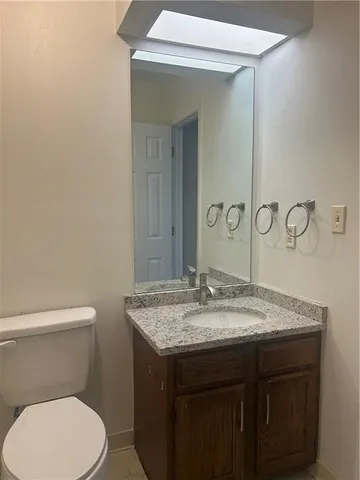 a bathroom with a granite countertop toilet sink and mirror