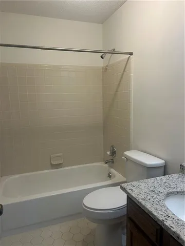 a bathroom with a granite countertop bathtub shower sink and toilet