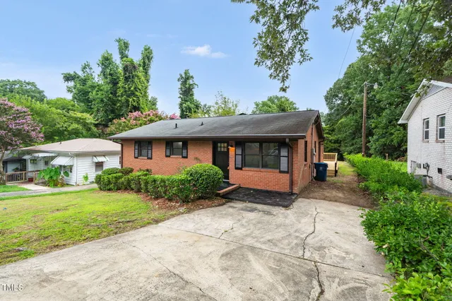 a front view of a house with a yard and potted plants