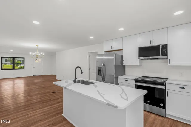 a kitchen with stainless steel appliances a sink a stove a refrigerator a microwave a sink and cabinets