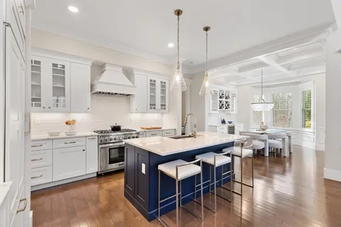 a kitchen with stainless steel appliances granite countertop a stove a sink a dining table and chairs with wooden floor