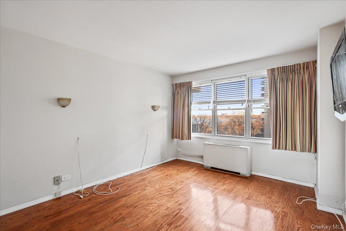 17-85 215th Street, Unit 5L Queens, NY 11360 - Photo 10 of 46 an empty room with wooden floor and windows
