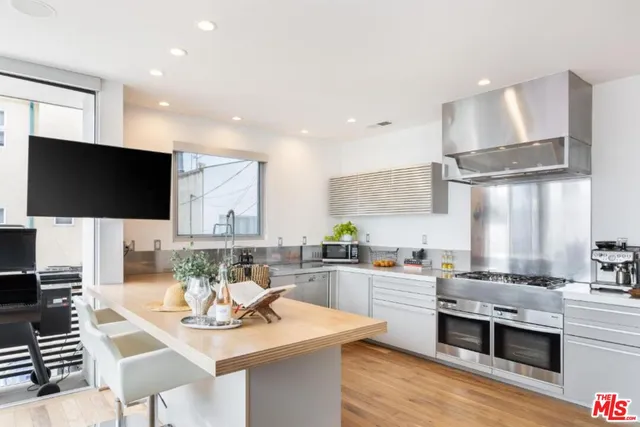 a kitchen with stainless steel appliances kitchen island granite countertop a sink dishwasher stove and oven with wooden floor