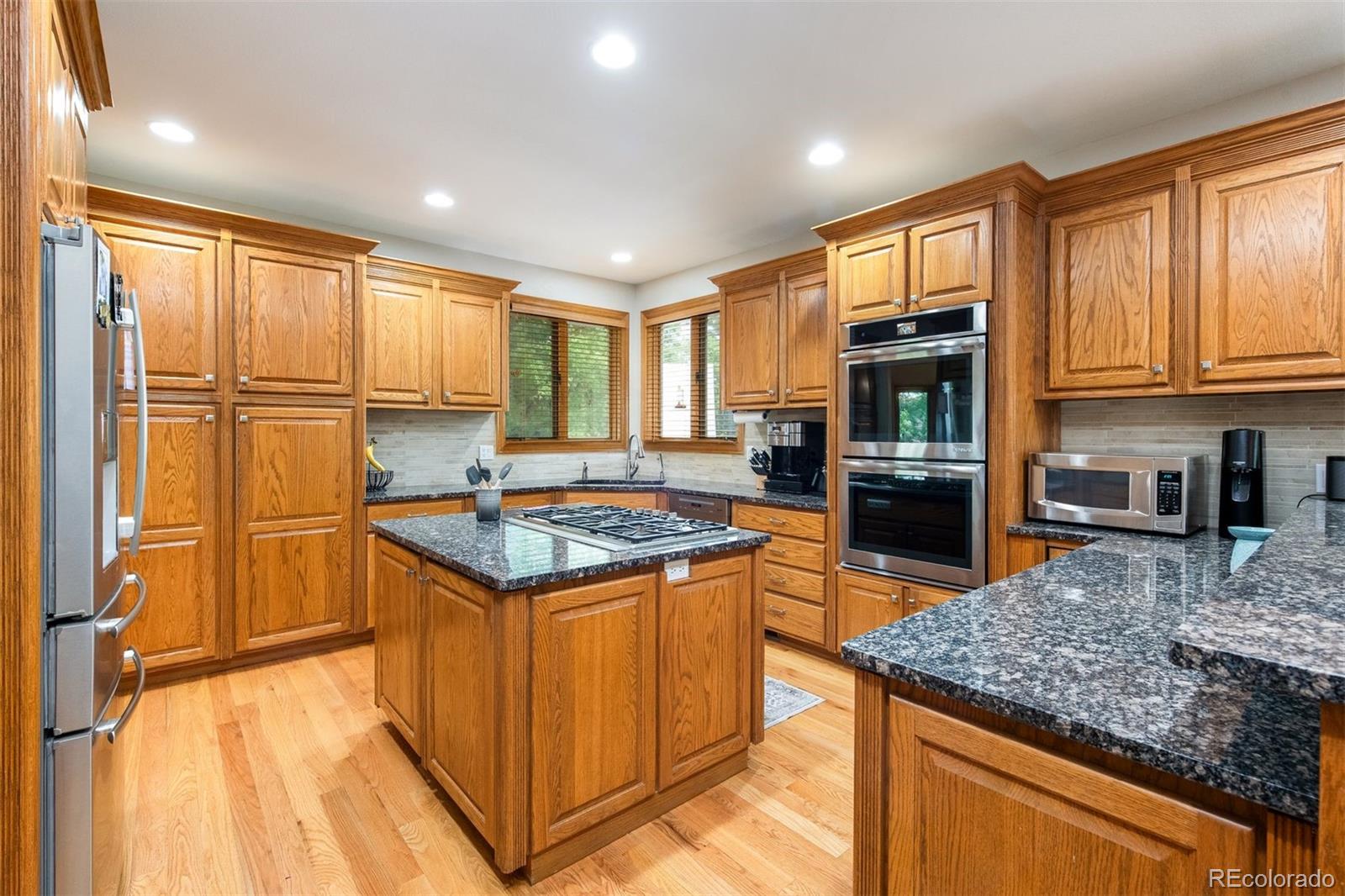 3935 Pierson Street Wheat Ridge, CO 80033 - Photo 19 of 50 a kitchen with stainless steel appliances granite countertop a stove top oven a sink dishwasher and a refrigerator with wooden floor
