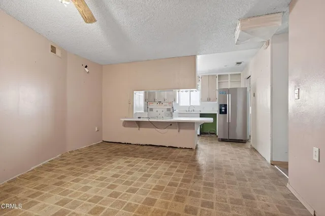 a view of an empty room with chandelier fan