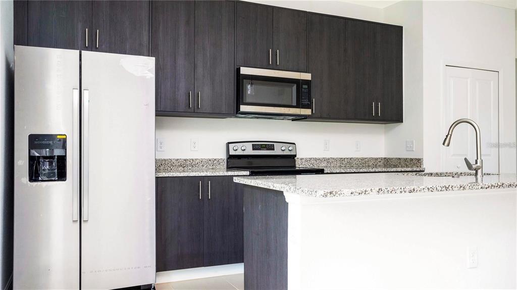 4147 Southwest 167th Street Ocala, FL 34473 - Photo 12 of 45 a kitchen with granite countertop a refrigerator and a microwave
