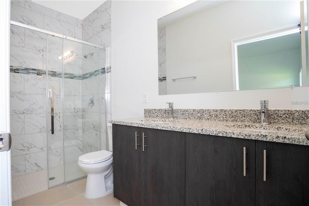 4147 Southwest 167th Street Ocala, FL 34473 - Photo 23 of 45 a bathroom with a granite countertop sink a toilet and shower