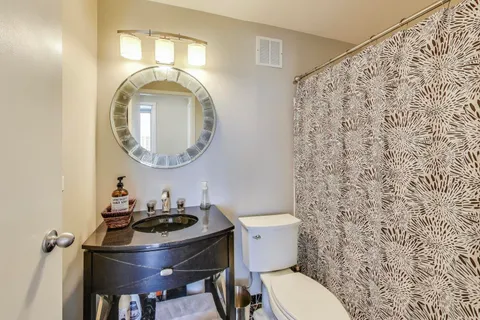 a bathroom with a granite countertop toilet a sink and a mirror