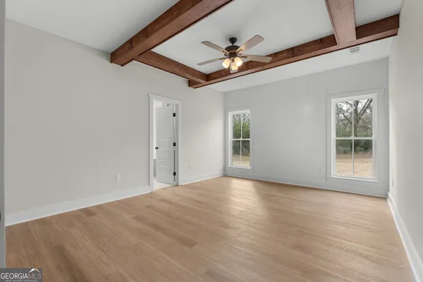 a view of empty room with wooden floor and fan