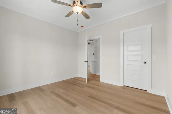 an empty room with wooden floor and chandelier fan