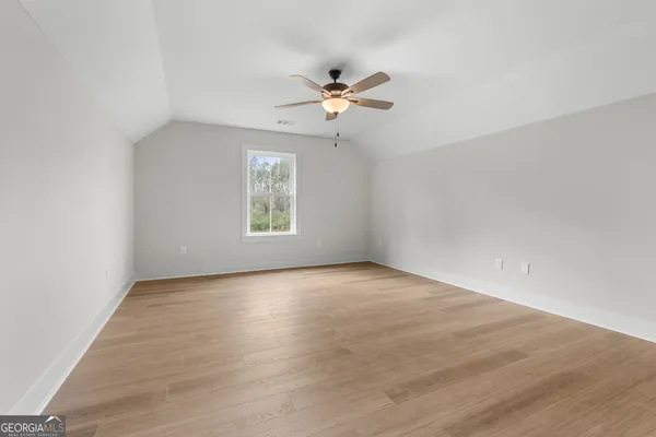 an empty room with wooden floor ceiling fan and windows
