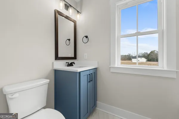 a bathroom with a toilet a sink a mirror and a window