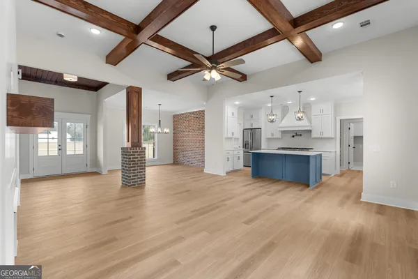 a view of an empty room with kitchen and a window