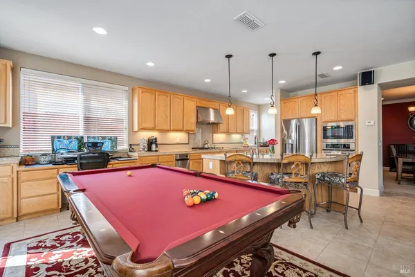 a kitchen with stainless steel appliances kitchen island granite countertop a dining table chairs sink and a granite counter top