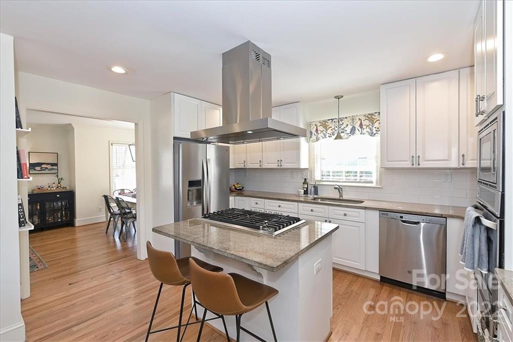 5638 Londonderry Road Charlotte, NC 28210 - Photo 18 of 44 a kitchen with stainless steel appliances granite countertop a stove top oven a sink a dining table and chairs with wooden floor