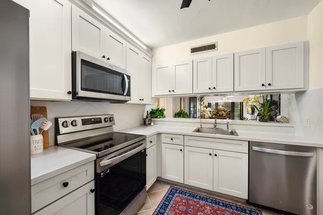 a kitchen with granite countertop a sink stainless steel appliances and cabinets