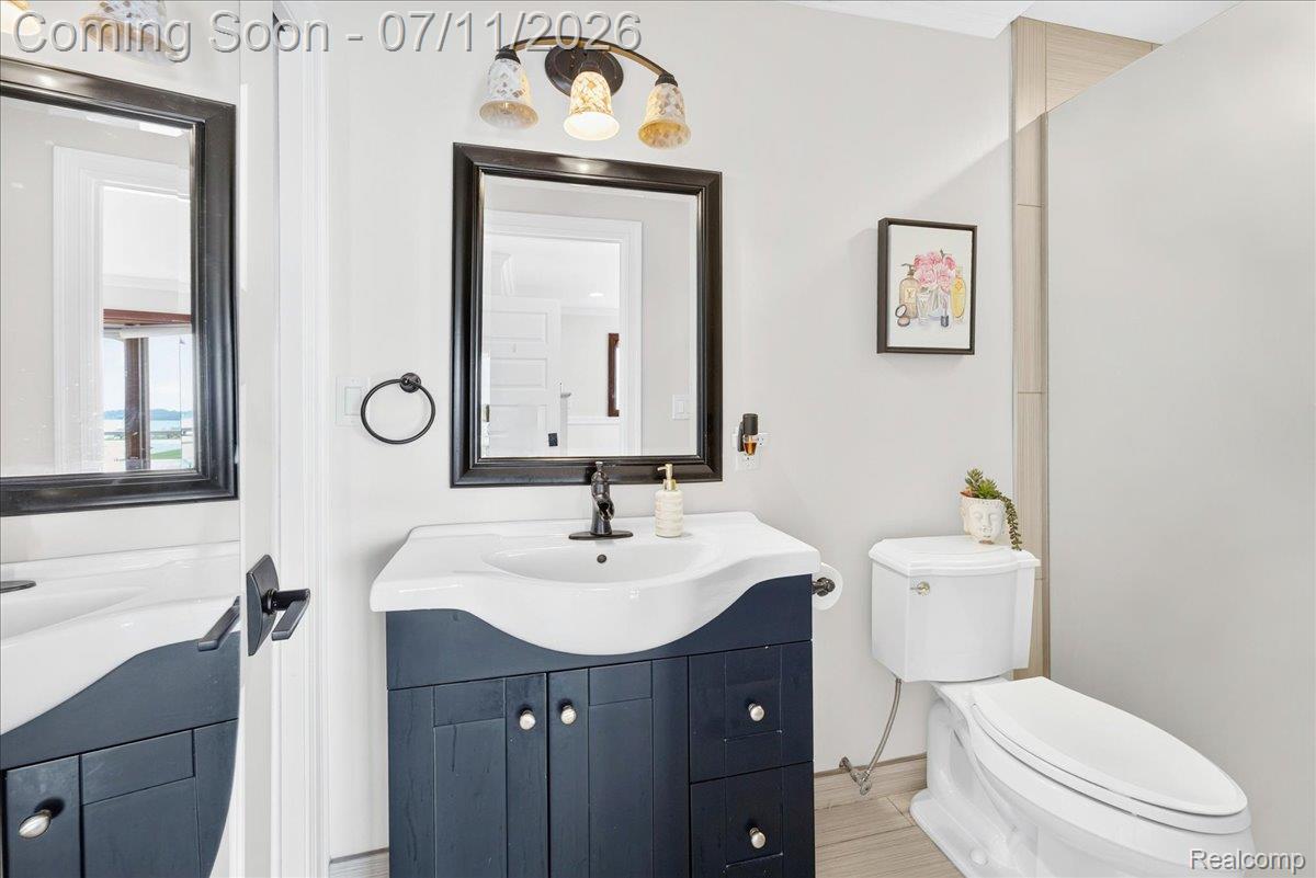 23750 East River Road Grosse Ile, MI 48138 - Photo 29 of 54 Bathroom featuring a dark wood-finish vanity with a white integrated sink, bronze-finish faucet, and coordinating framed mirror