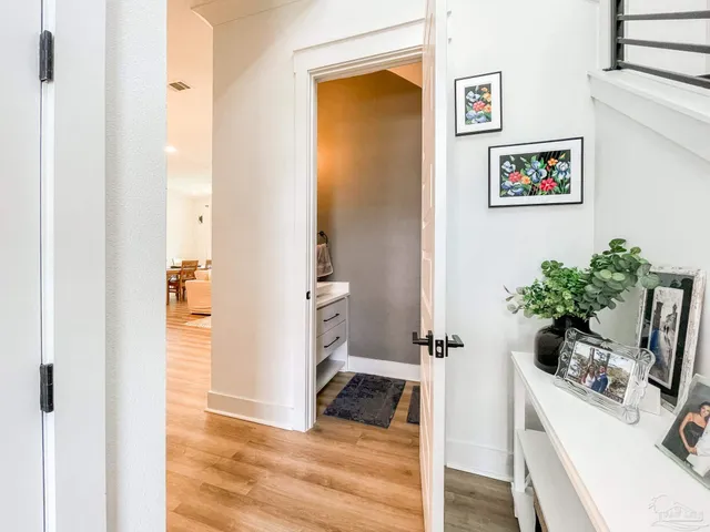 a view of a hallway with wooden floor and a bathroom