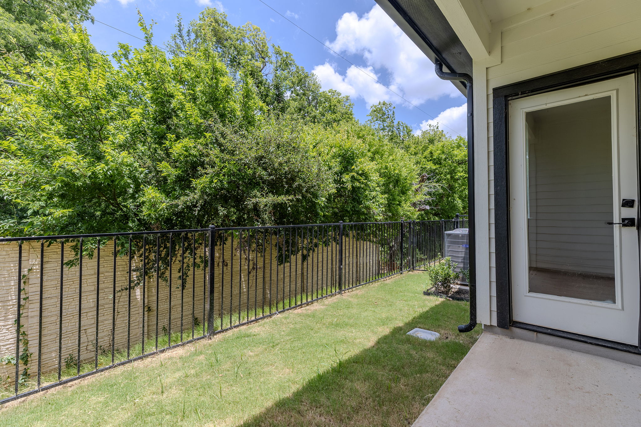 2600 Gattis School Road, Unit 1002 Round Rock, TX 78664 - Photo 32 of 40 A verdant backyard with a manicured lawn is enclosed by a wrought iron fence, offering a private outdoor retreat.