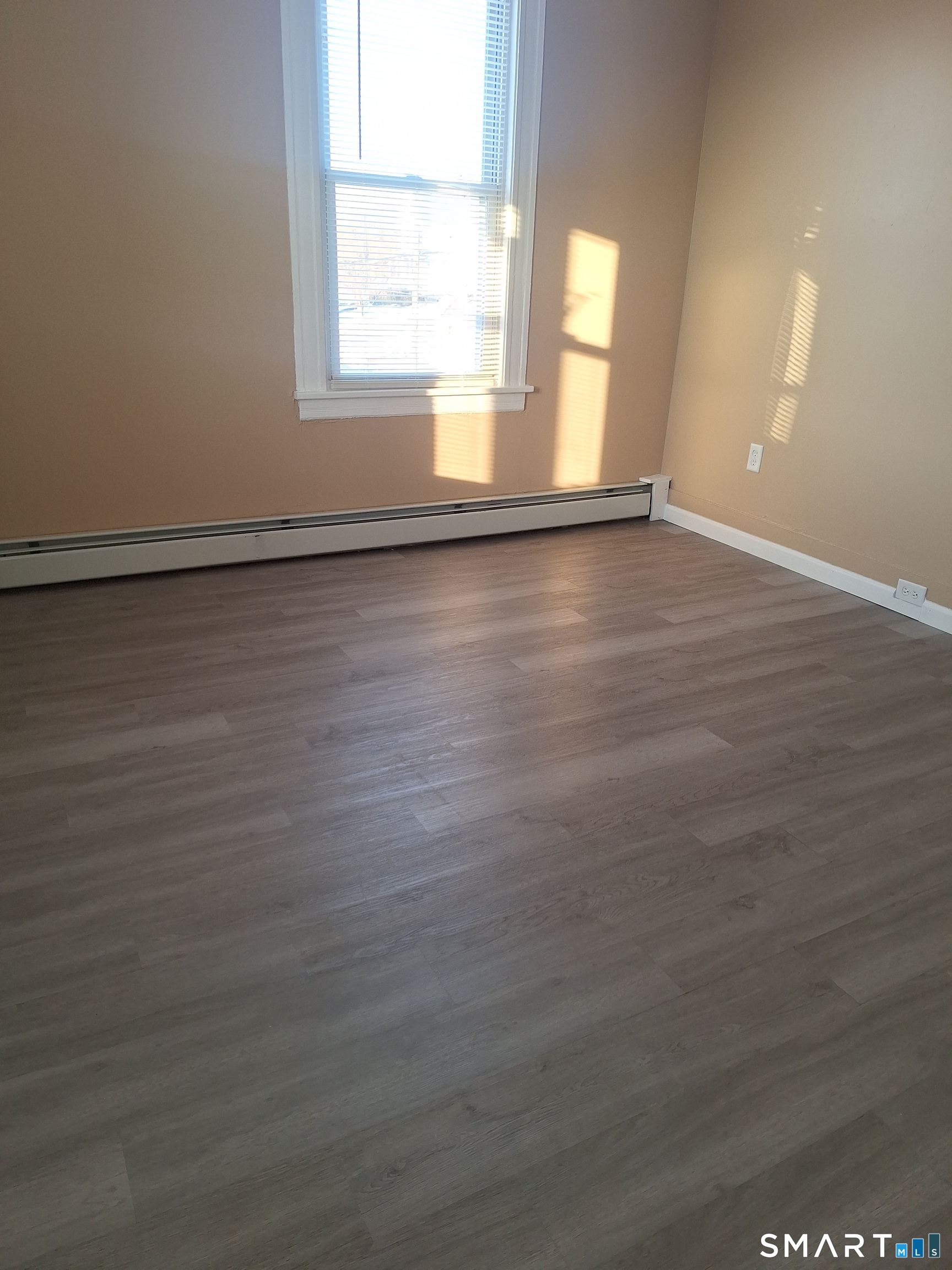 23 1/2 North Spring Street, Unit 3 Ansonia, CT 06401 - Photo 5 of 12 an empty room with wooden floor and windows