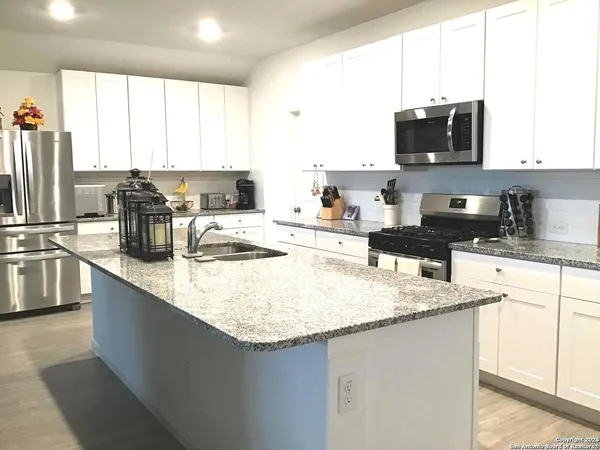 a kitchen with stainless steel appliances granite countertop a sink a stove and a refrigerator