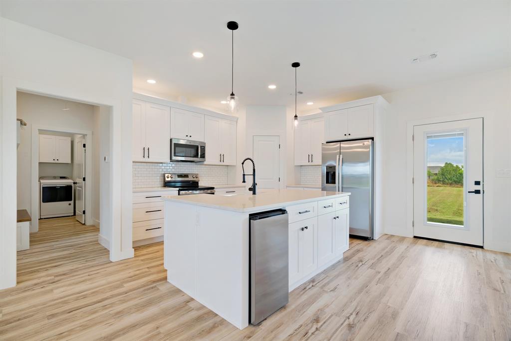 204 Private Road Sumner, TX 75486 - Photo 8 of 25 a kitchen with stainless steel appliances kitchen island granite countertop a refrigerator a sink a stove and oven with wooden floor
