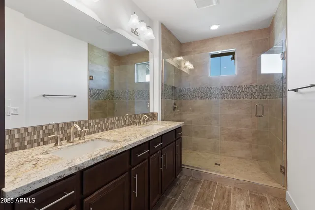 a bathroom with a granite countertop sink a mirror and a shower