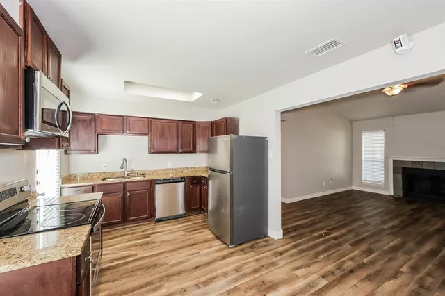 a kitchen with stainless steel appliances granite countertop a refrigerator and a stove top oven