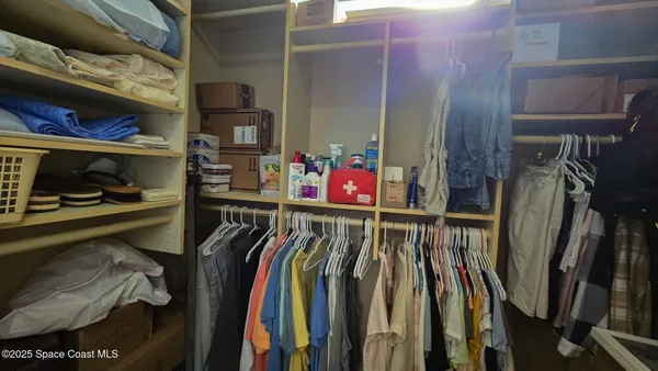 a view of walk in closet with clothes and shoes