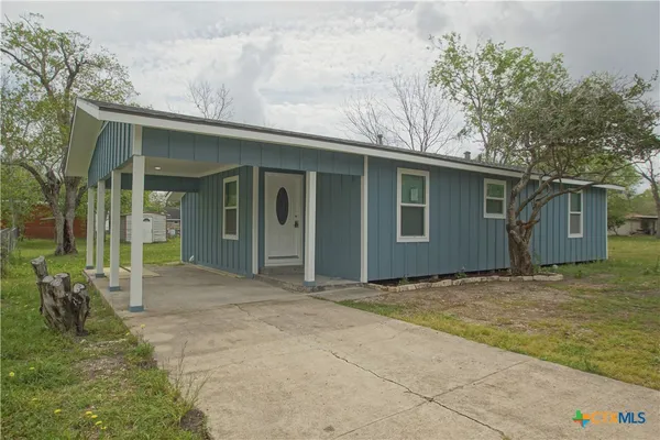 a view of a house with backyard and a tree