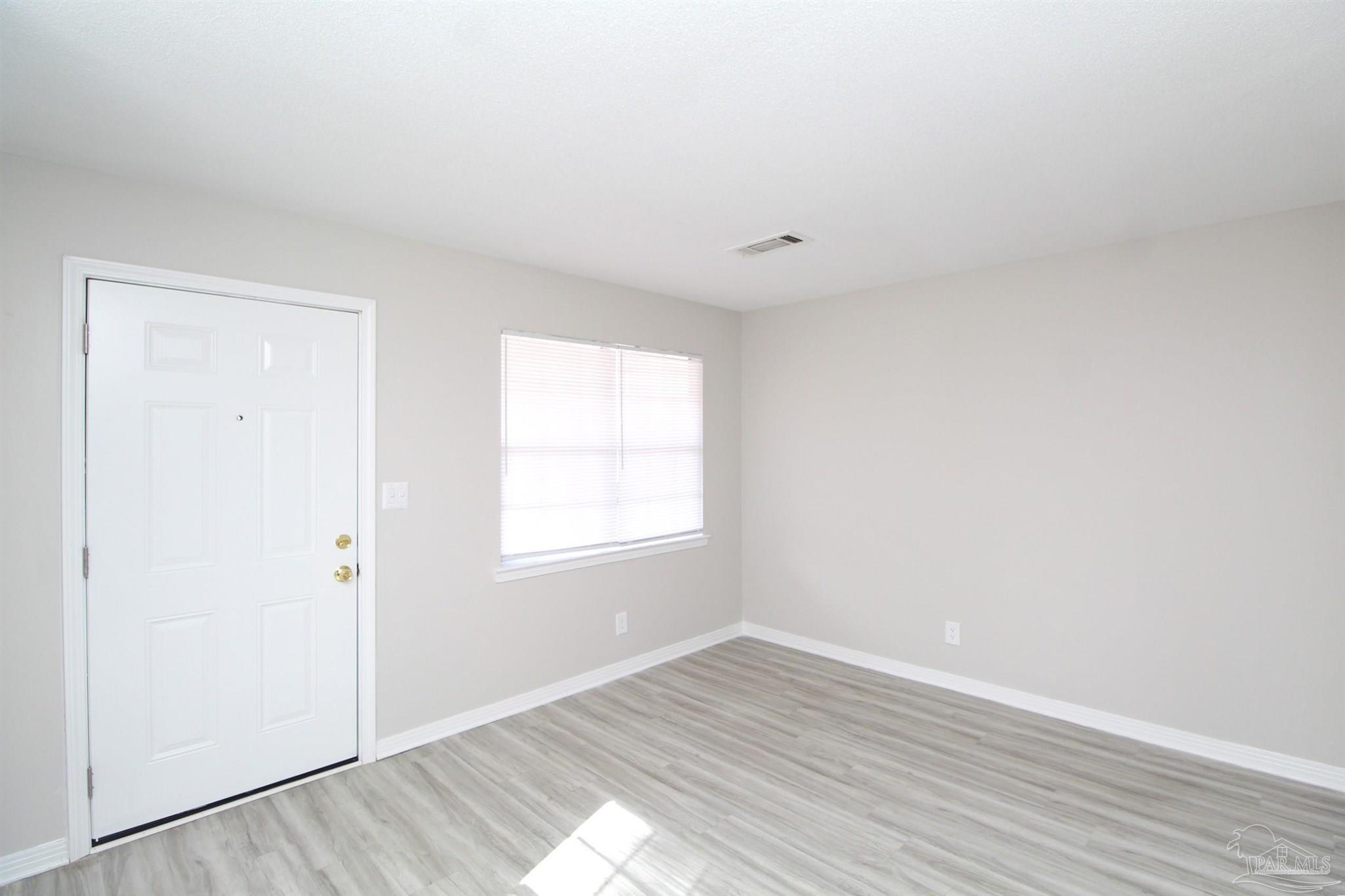 10151 Guidy Lane, Unit B2 Pensacola, FL 32514 - Photo 3 of 11 an empty room with wooden floor and windows