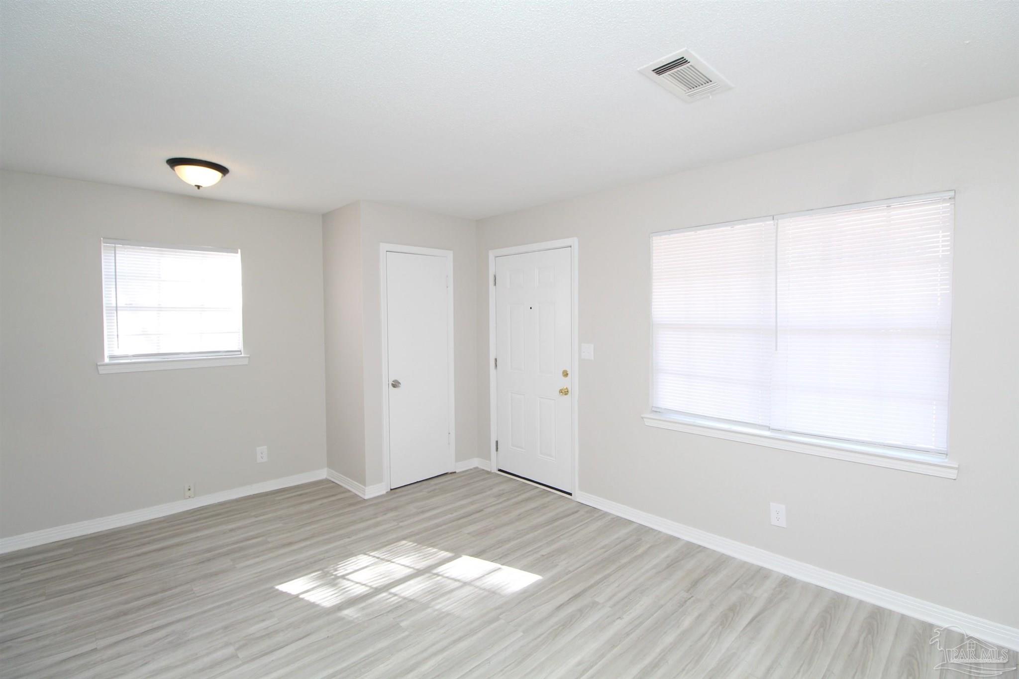 10151 Guidy Lane, Unit B2 Pensacola, FL 32514 - Photo 4 of 11 an empty room with wooden floor and windows