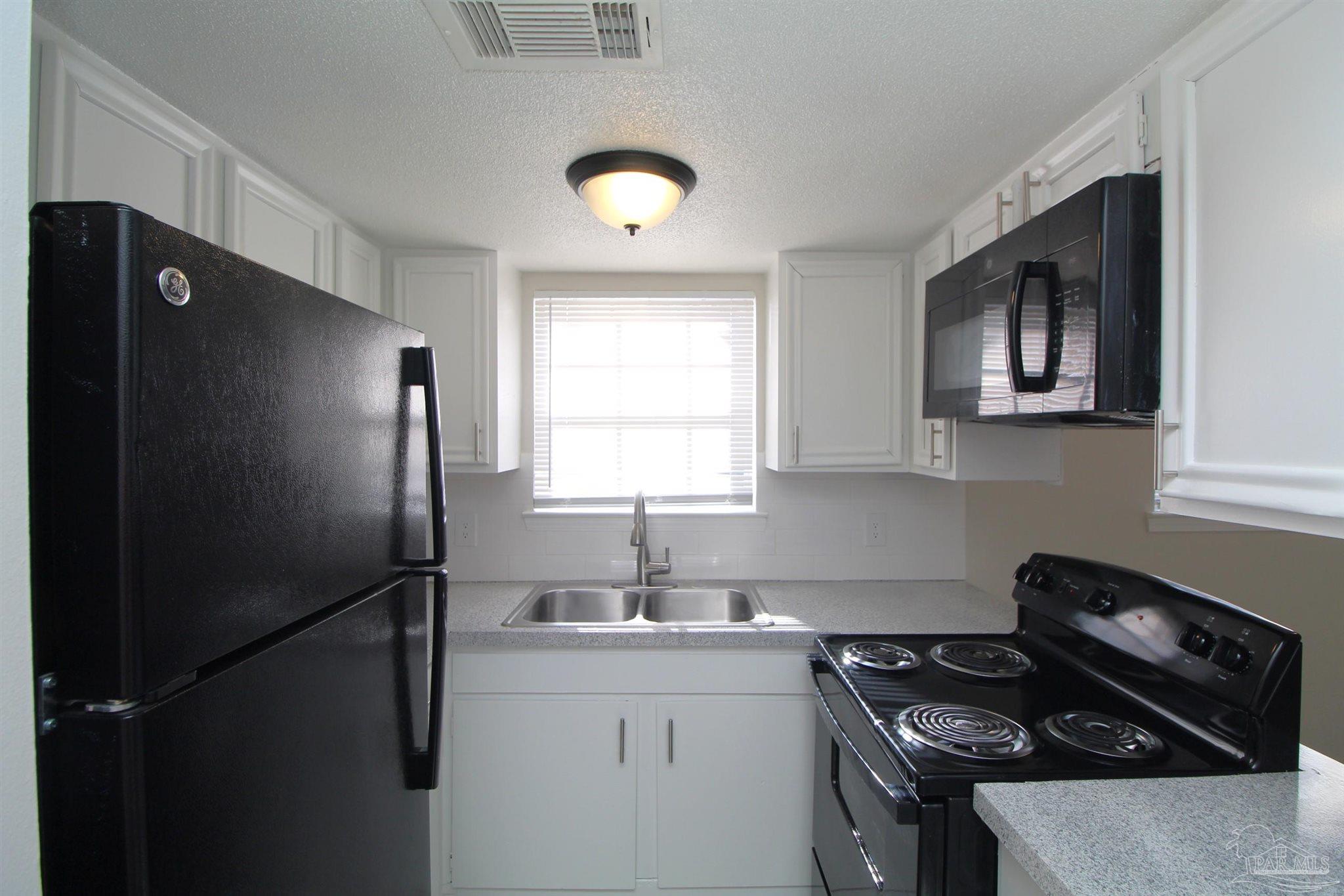 10151 Guidy Lane, Unit B2 Pensacola, FL 32514 - Photo 7 of 11 a kitchen with a refrigerator and a stove top oven
