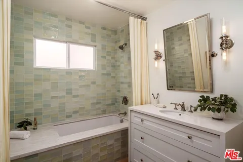 a bathroom with a bathtub shower sink and mirror
