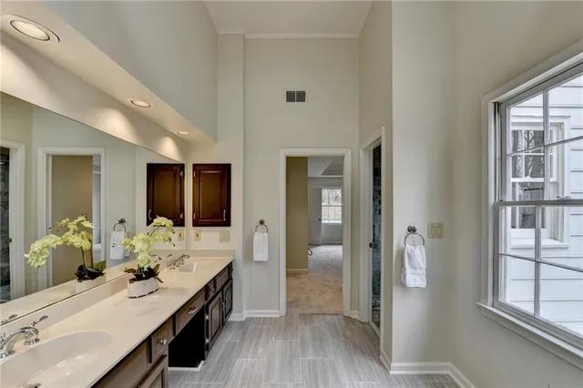 a bathroom with a double vanity sink a mirror and next to a window