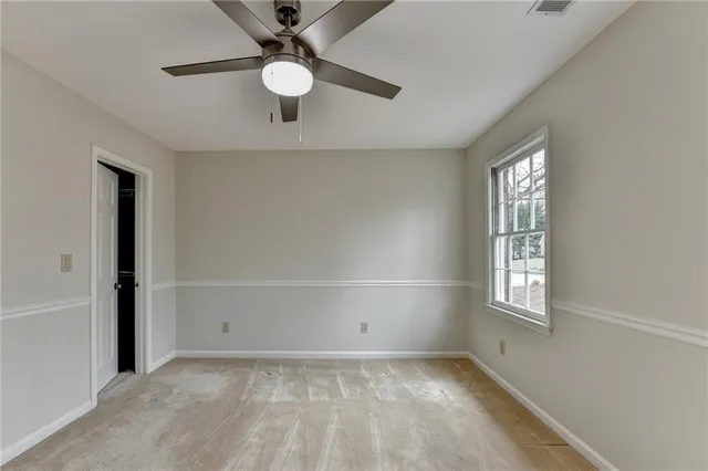 an empty room with windows and fan