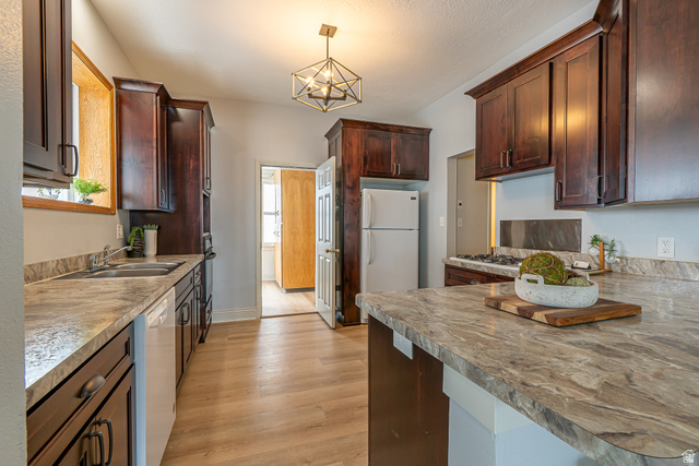 33 North 200 East Logan, UT 84321 - Photo 12 of 54 Kitchen with white appliances, hanging light fixtures, light wood-style floors, a chandelier, and a peninsula