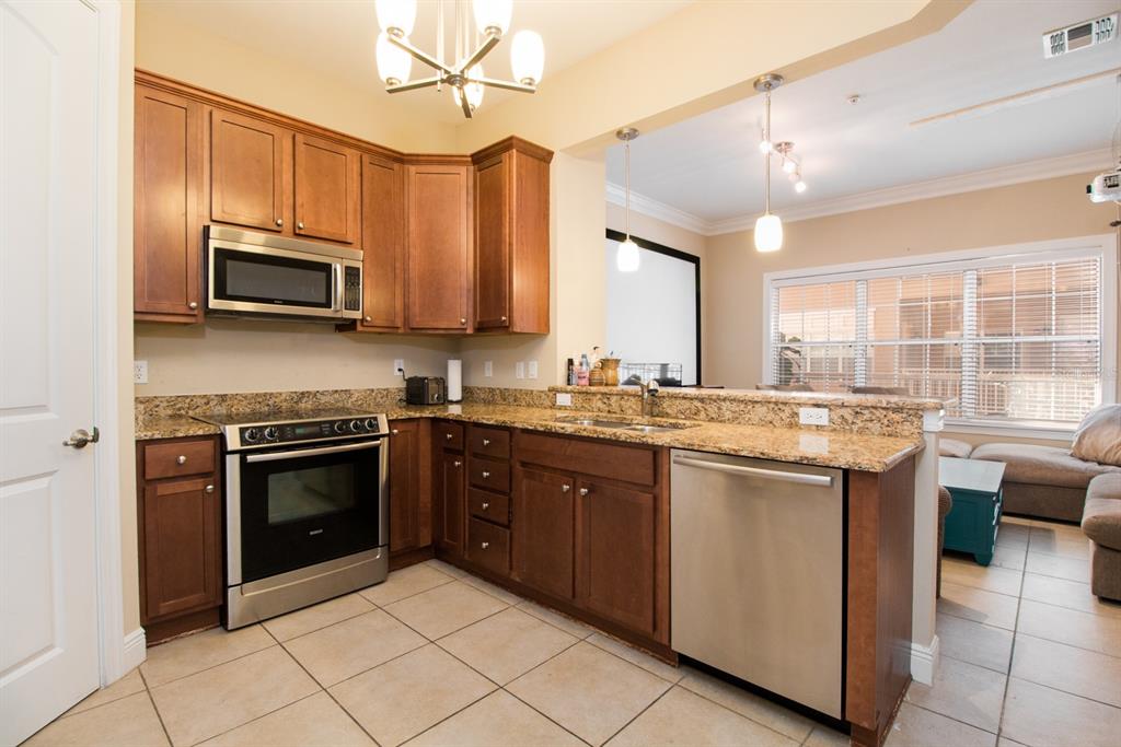 230 Southwest 2nd Avenue, Unit 207 Gainesville, FL 32601 - Photo 5 of 25 a kitchen with stainless steel appliances granite countertop a stove a sink and a microwave