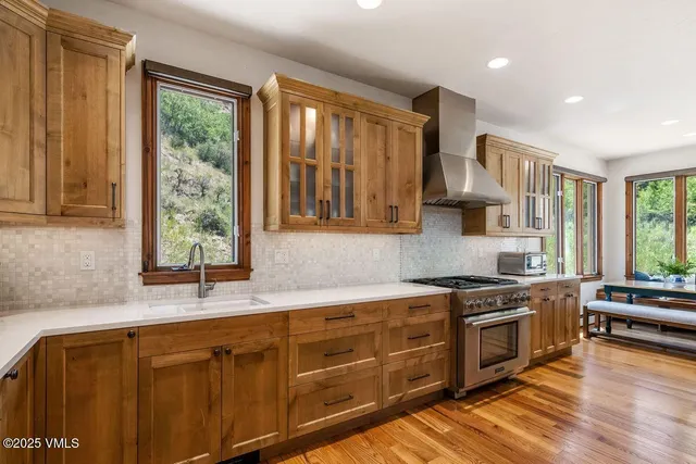 a kitchen with stainless steel appliances granite countertop a sink a stove cabinets counter space and a window