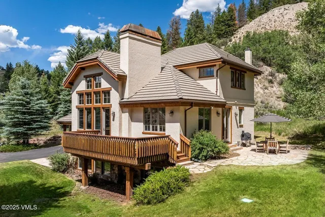 a front view of a house with garden and trees