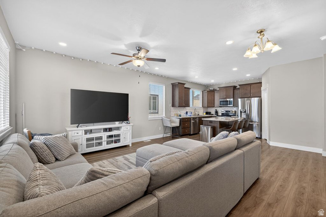 412 McClellan Court Provo, UT 84601 - Photo 2 of 20 Living room with light wood finished floors, a chandelier, and ceiling fan