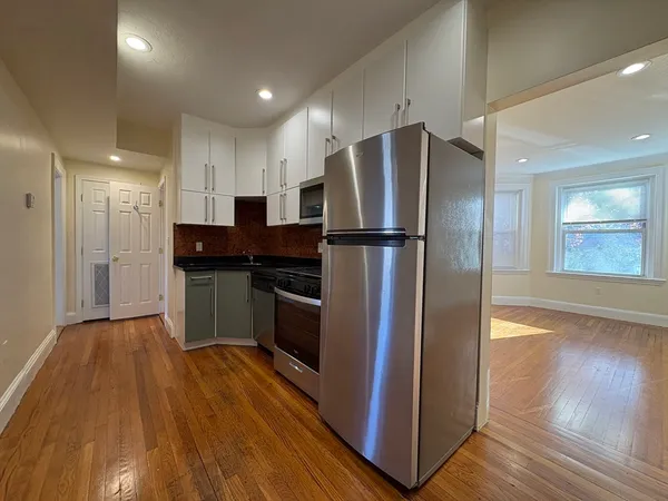 a kitchen with kitchen island wooden floors appliances and cabinets