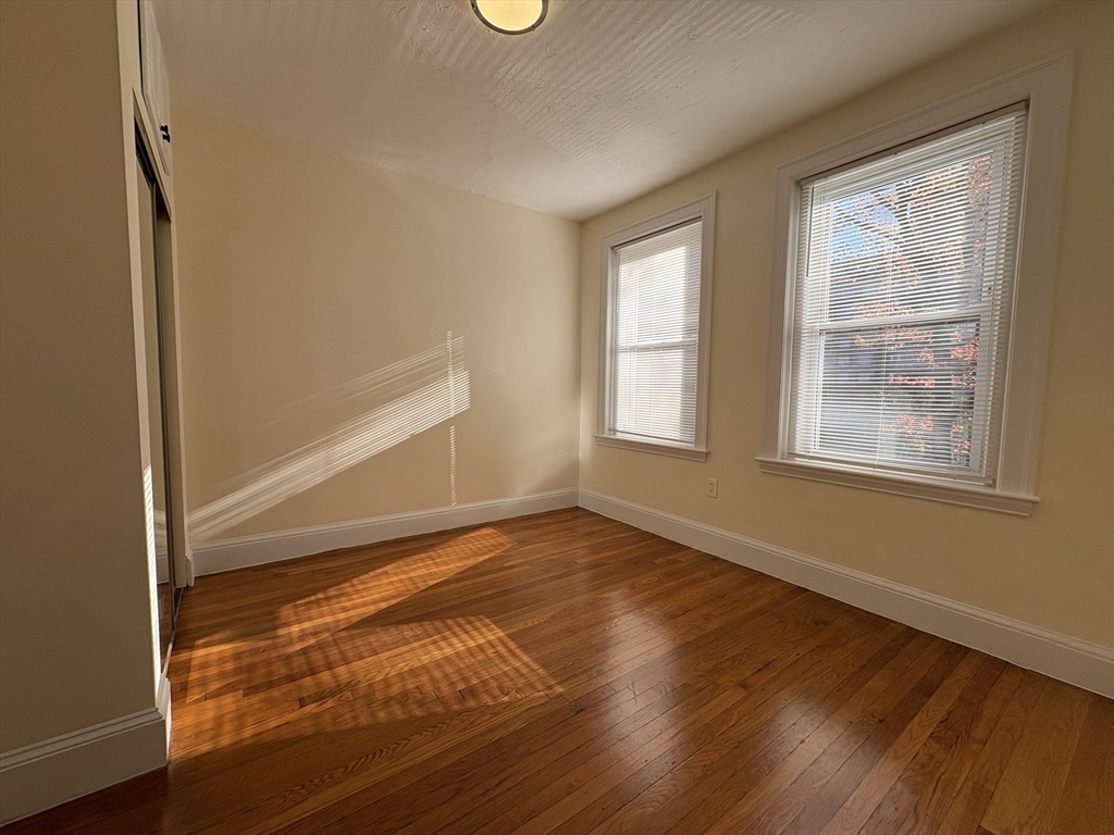 73 Thatcher Street, Unit 202 Brookline, MA 02446 - Photo 4 of 15 a view of an empty room with wooden floor and a window