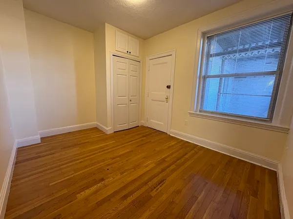 a view of an empty room and wooden floor and cabinet
