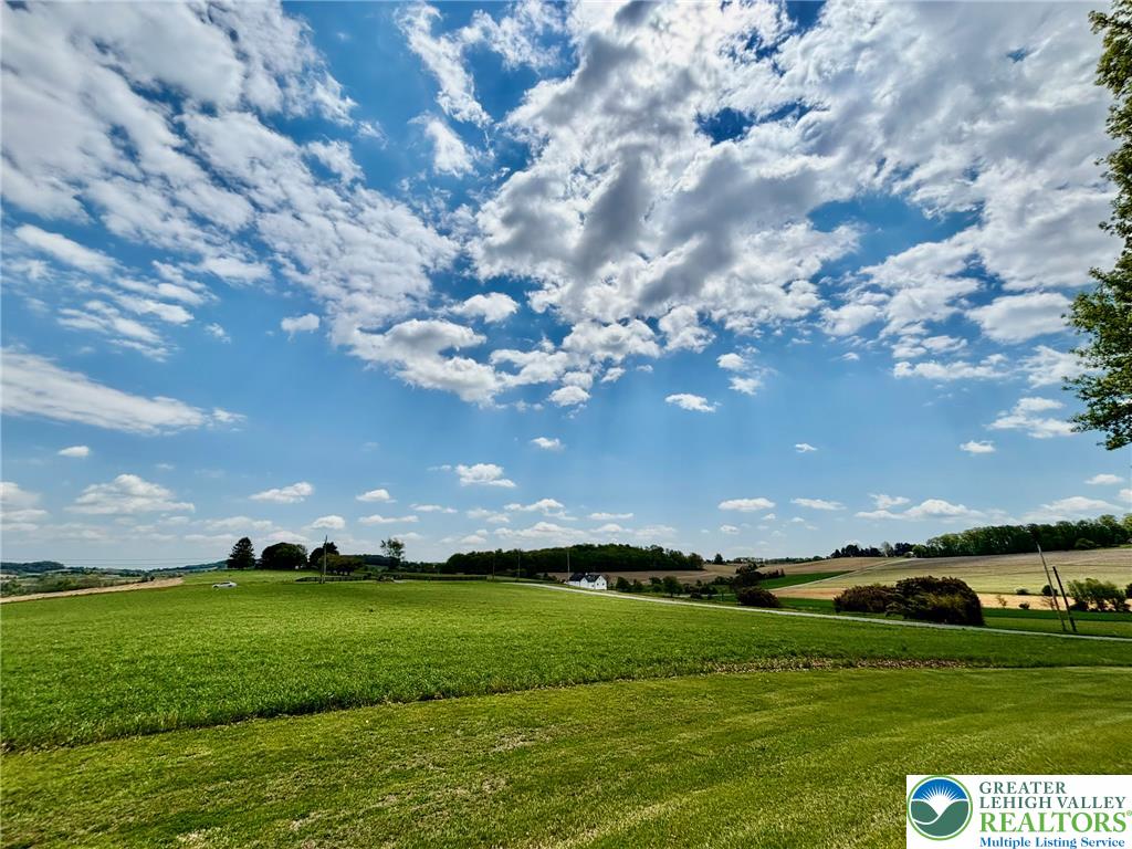 Expansive green fields unfold under a brilliant sky, offering serene rural tranquility.