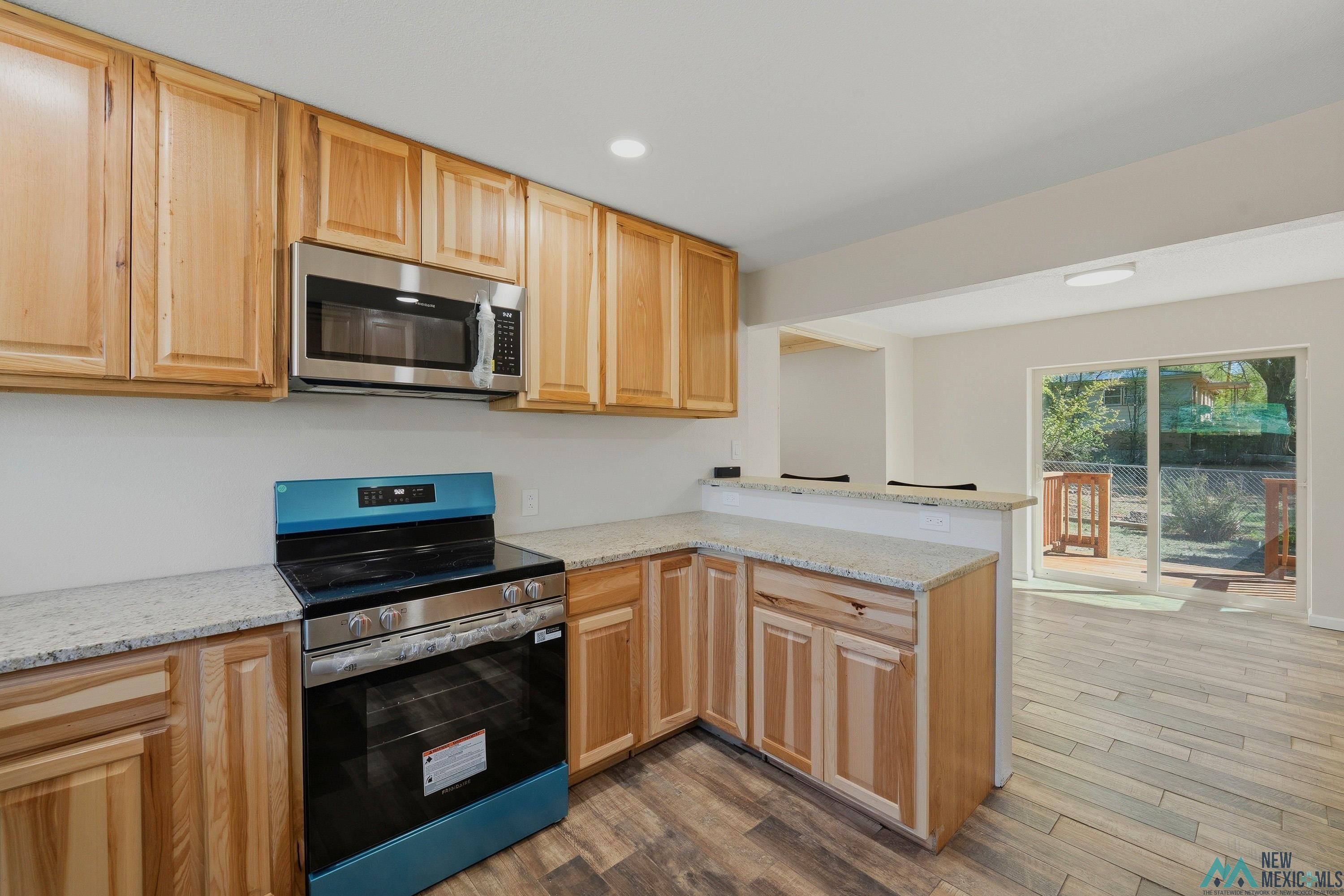 544 South 13th Avenue Raton, NM 87740 - Photo 12 of 37 Kitchen featuring wood cabinetry, light-toned countertops, and stainless steel appliances, including an oven range and an over-the-range microwave