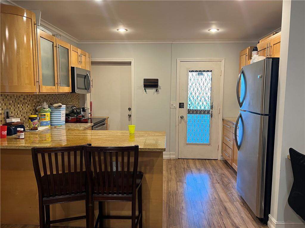 1250 East Sample Road, Unit 208 Pompano Beach, FL 33064 - Photo 3 of 19 a kitchen with stainless steel appliances granite countertop a refrigerator a stove a sink dishwasher and a dining table with wooden floor