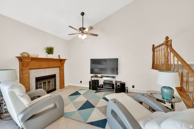 5057 South Ridgedale Drive Ogden, UT 84403 - Photo 22 of 69 Living area featuring a vaulted ceiling with a ceiling fan, a fireplace with a wood-finish mantel and tiled surround, and a wooden staircase with baluster railing