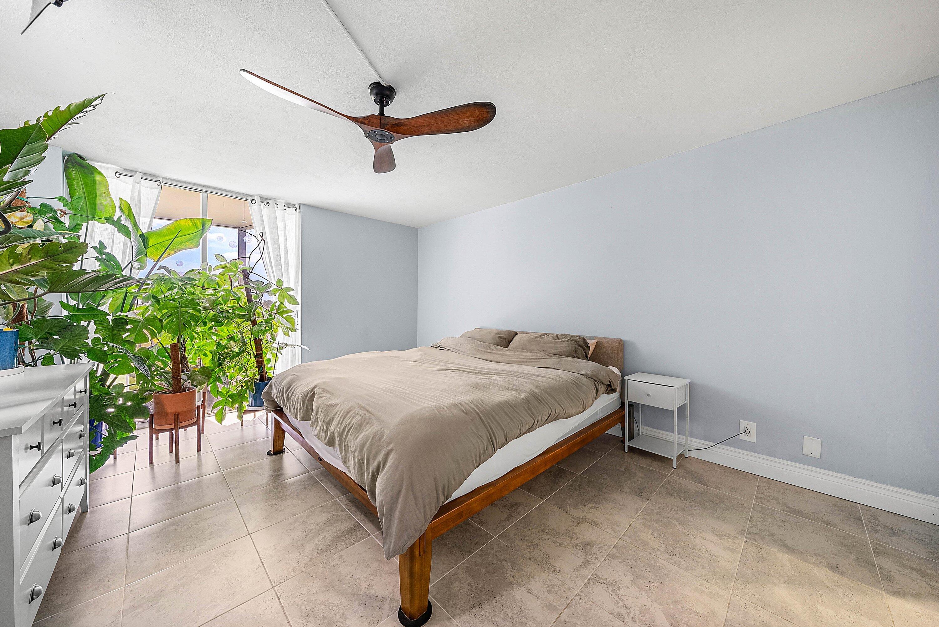 6699 Northwest 2nd Avenue, Unit 415 Boca Raton, FL 33487 - Photo 14 of 27 a bed sitting in a room next to a potted plant